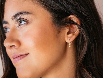 A person wearing short, chain loop earrings.