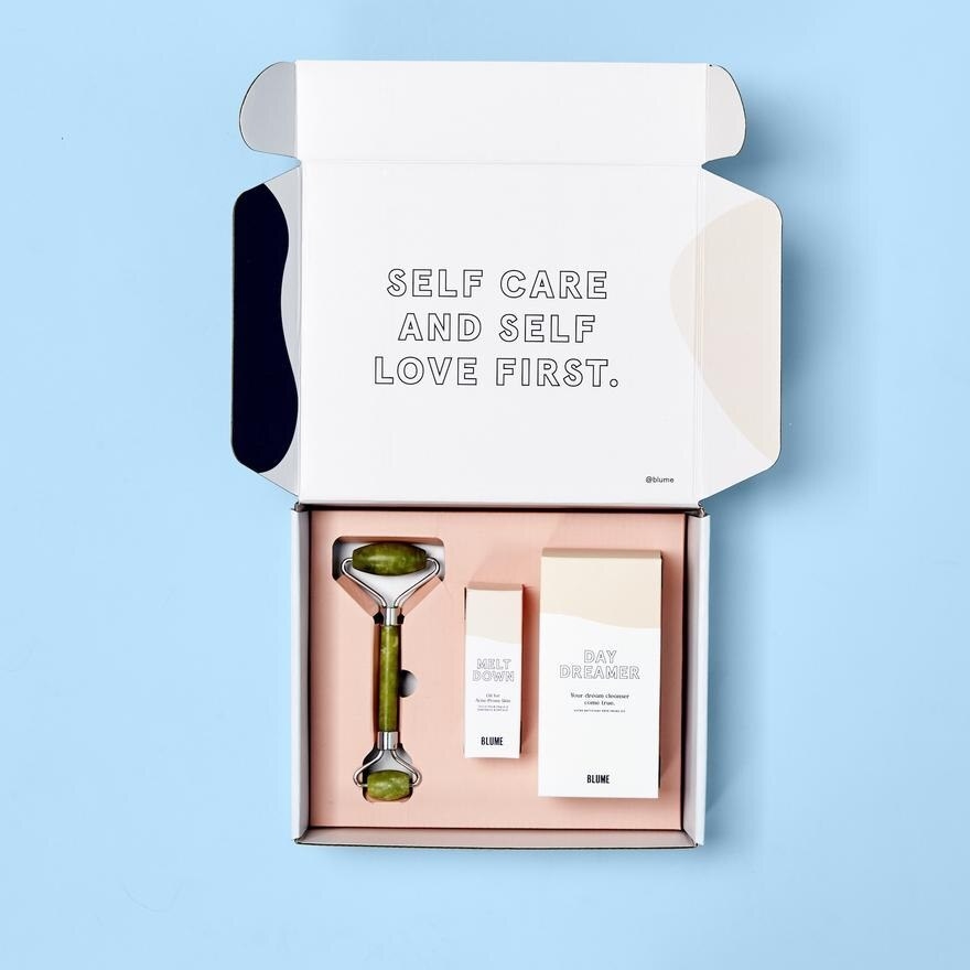 A box with a facial roller and two bottles of beauty product inside