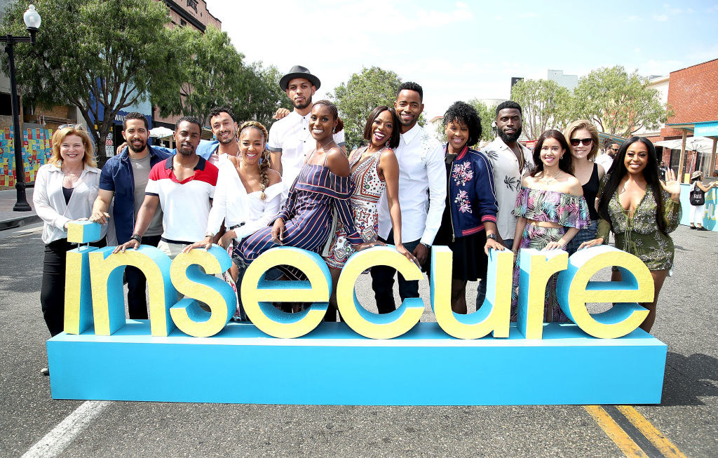 The cast of Insecure standing behind a sign with the name of the show