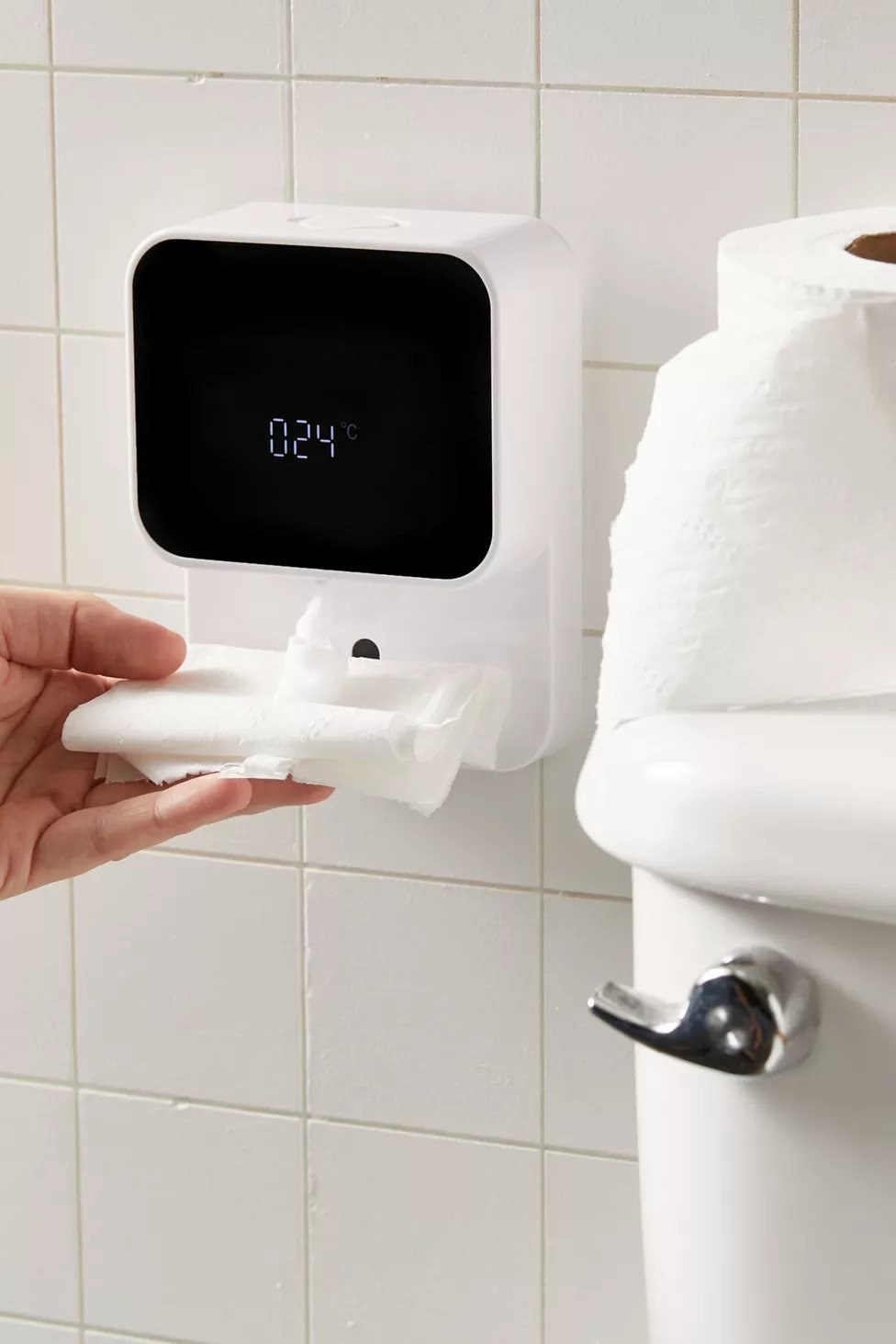 hand holding dry tissue paper under the wall mounted foam dispenser. the screen shows the room&#x27;s temperature.