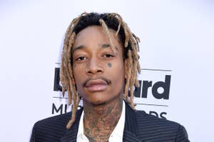 Wiz Khalifa poses for the camera with his hands in his pockets while wearing a suit and button-down shirt
