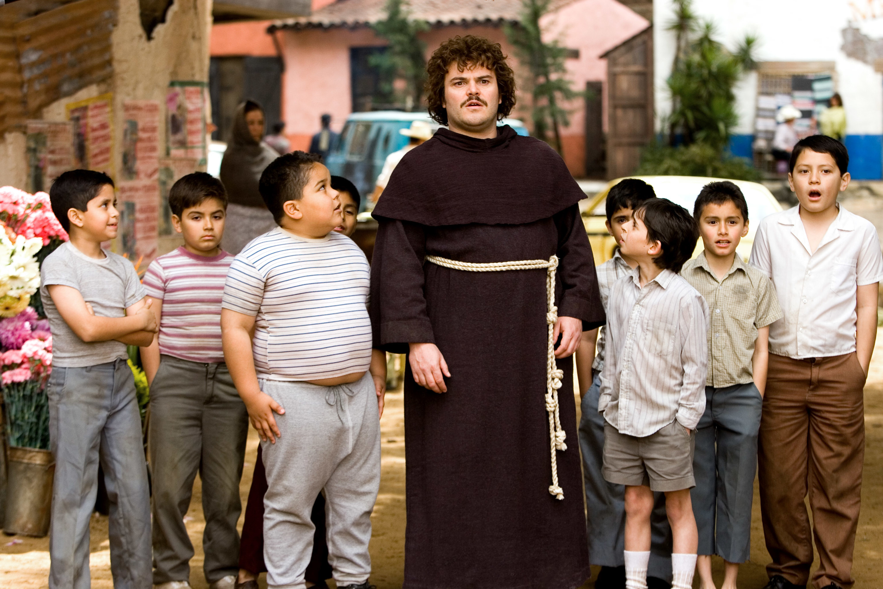 Nacho Libre in a friar&#x27;s frock surrounded by orphans