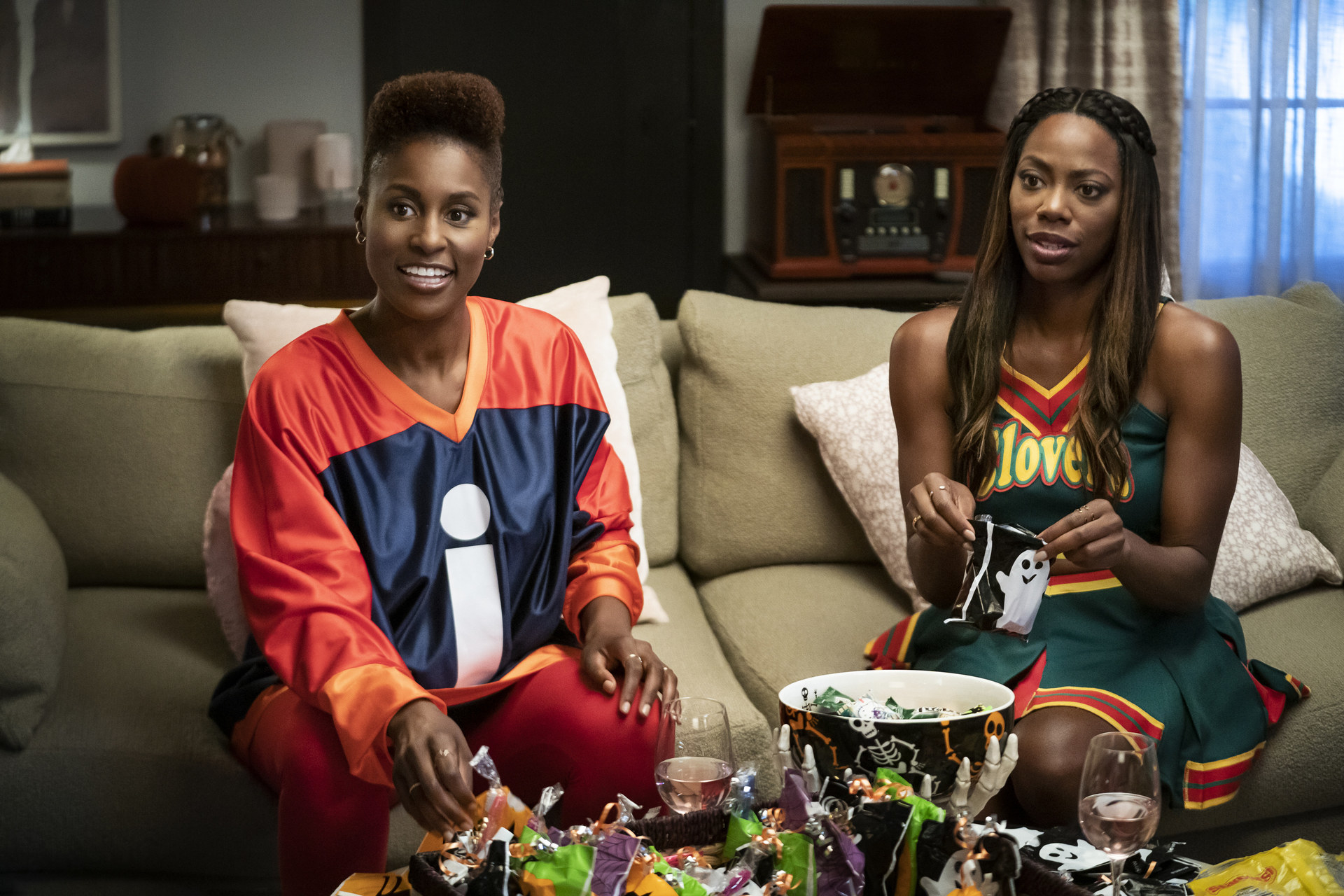 Issa and Molly sit on a couch in their Halloween costumes