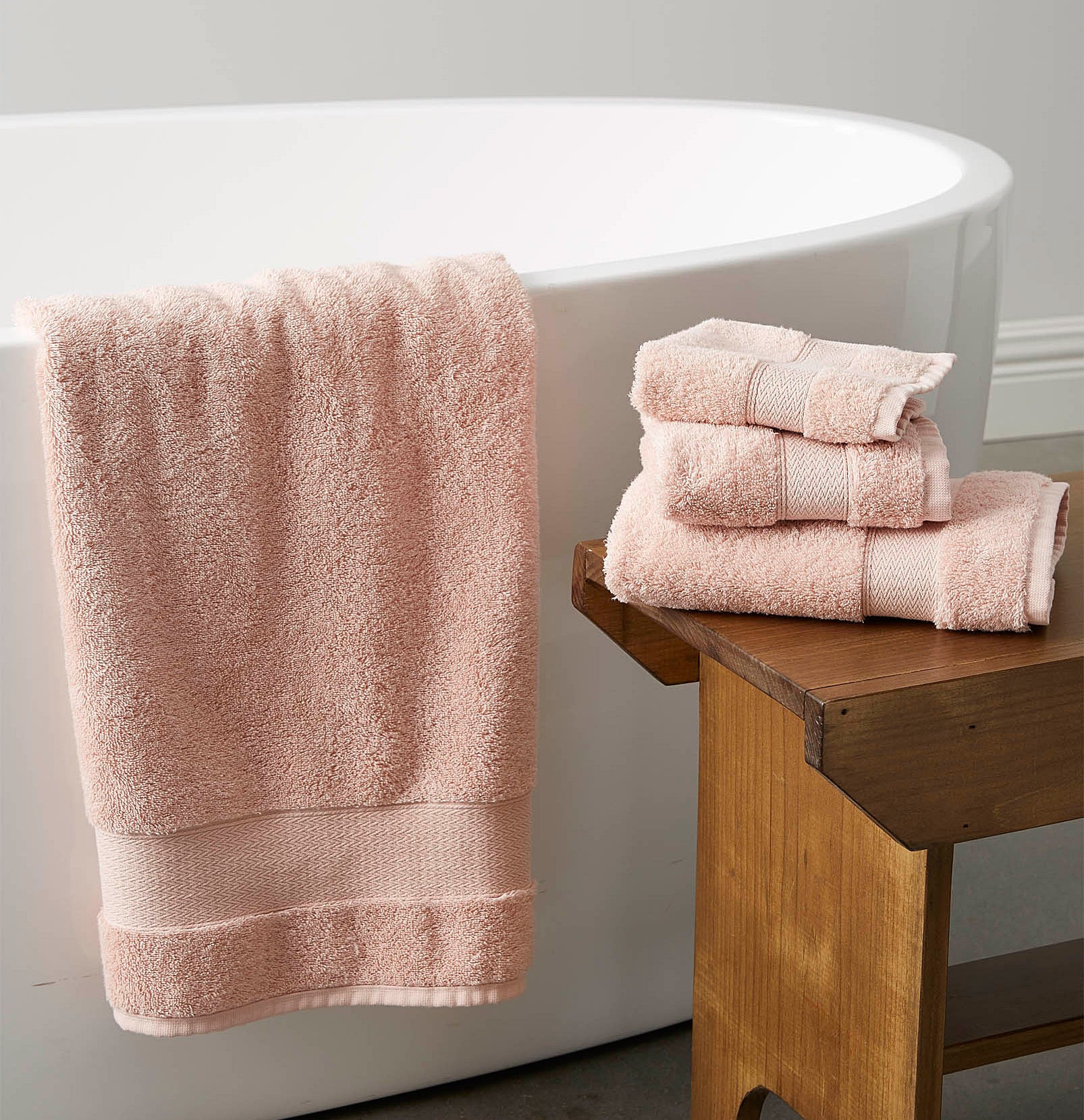 a set of fluffy bath towels arranged around a freestanding bathtub