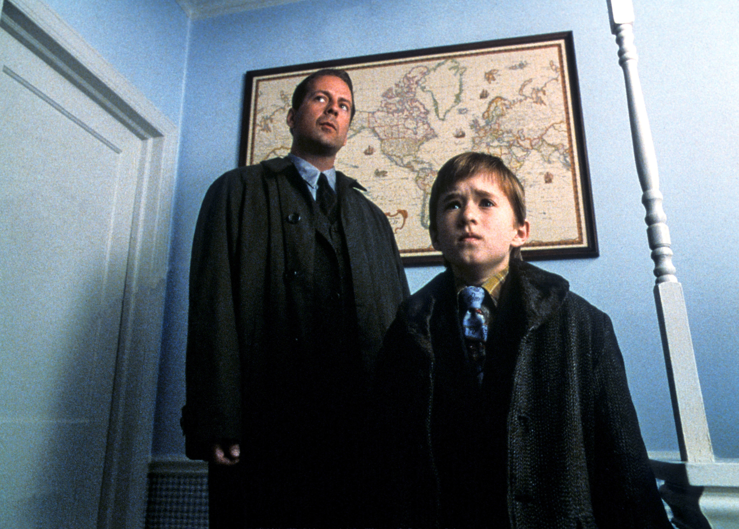 Bruce Willis and Haley Joel Osment stand in a bedroom