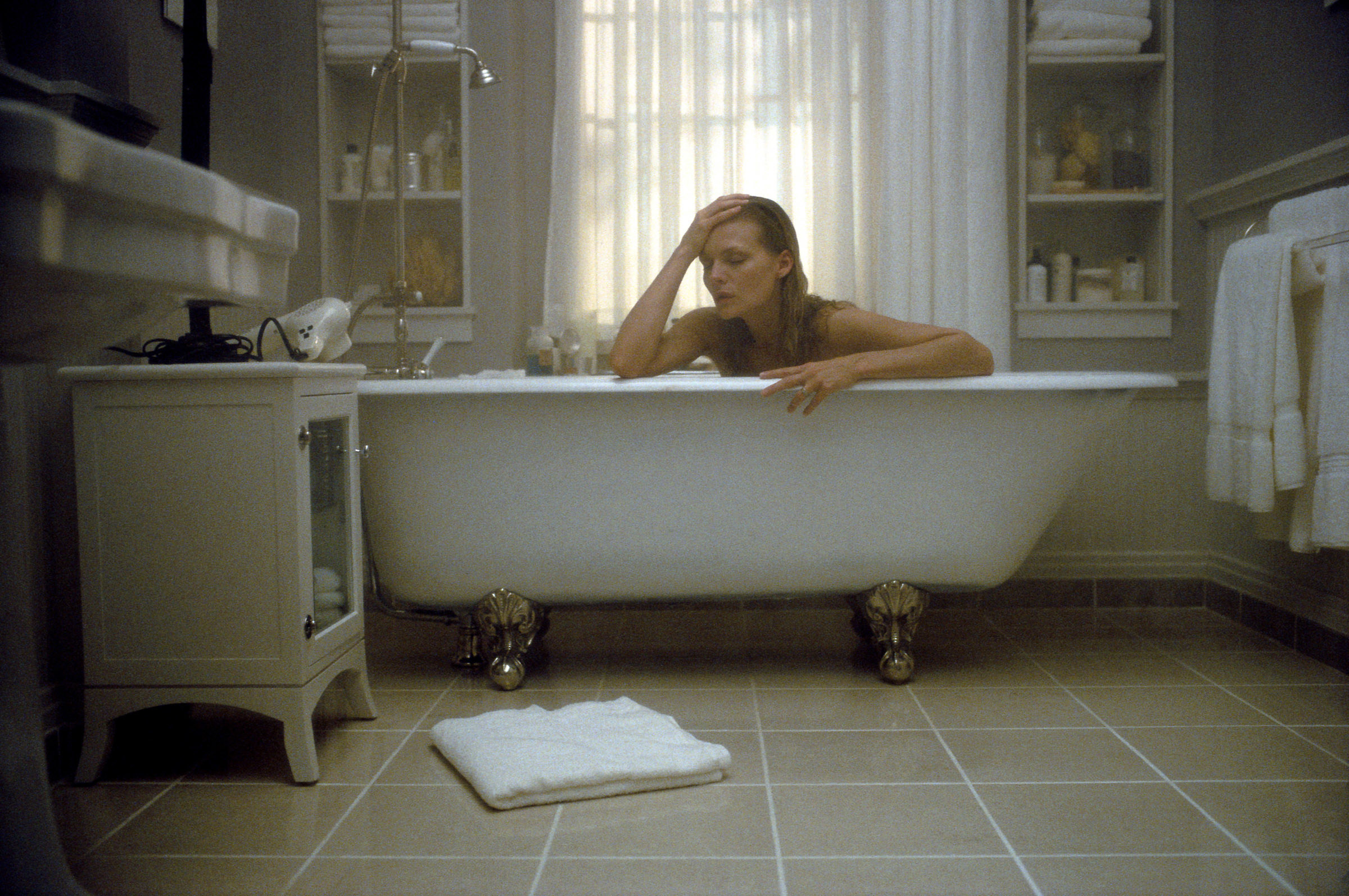 Michelle Pfeiffer sits in a bathtub looking distressed