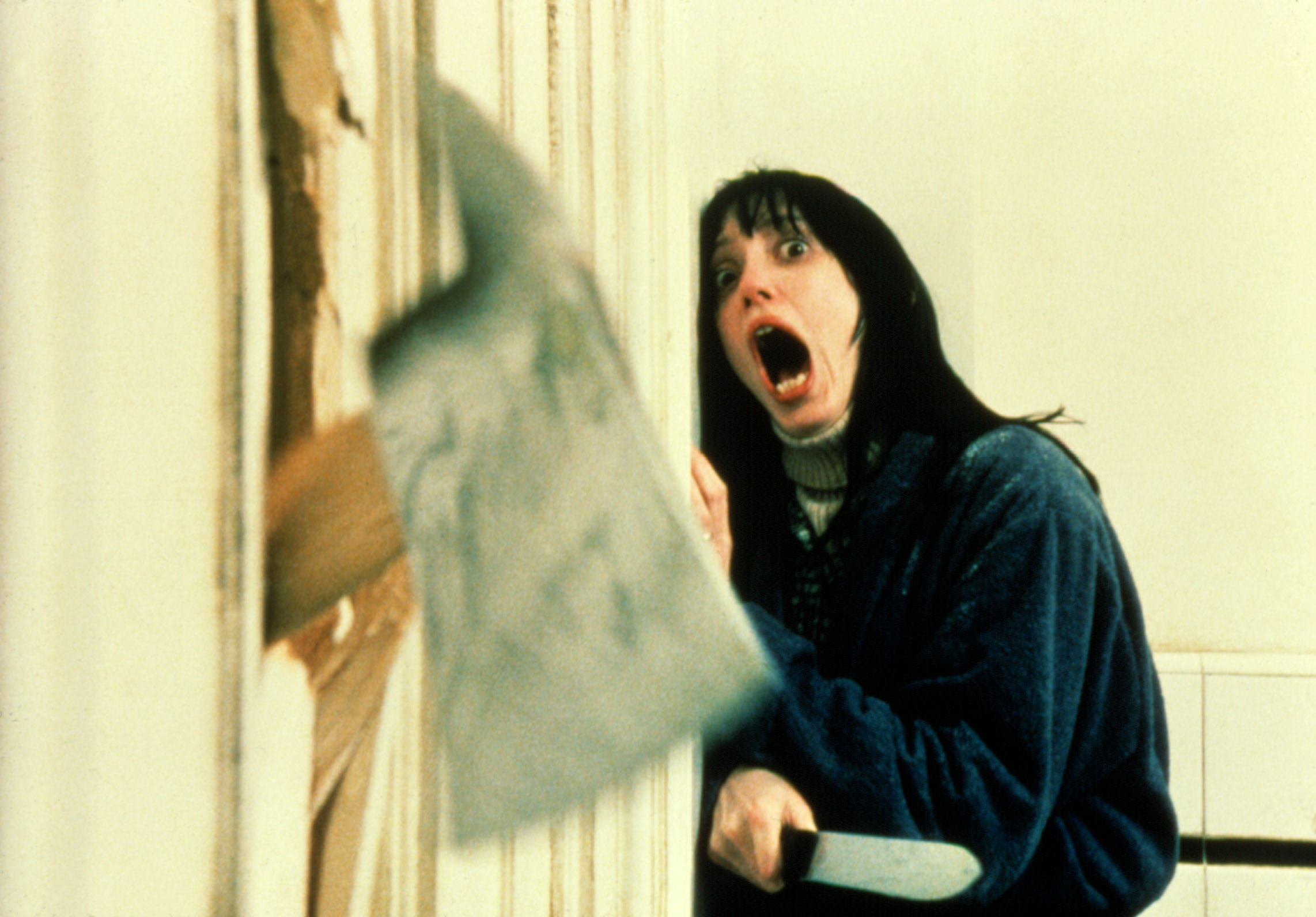 Shelley Duvall screams while an axe breaks down the door.