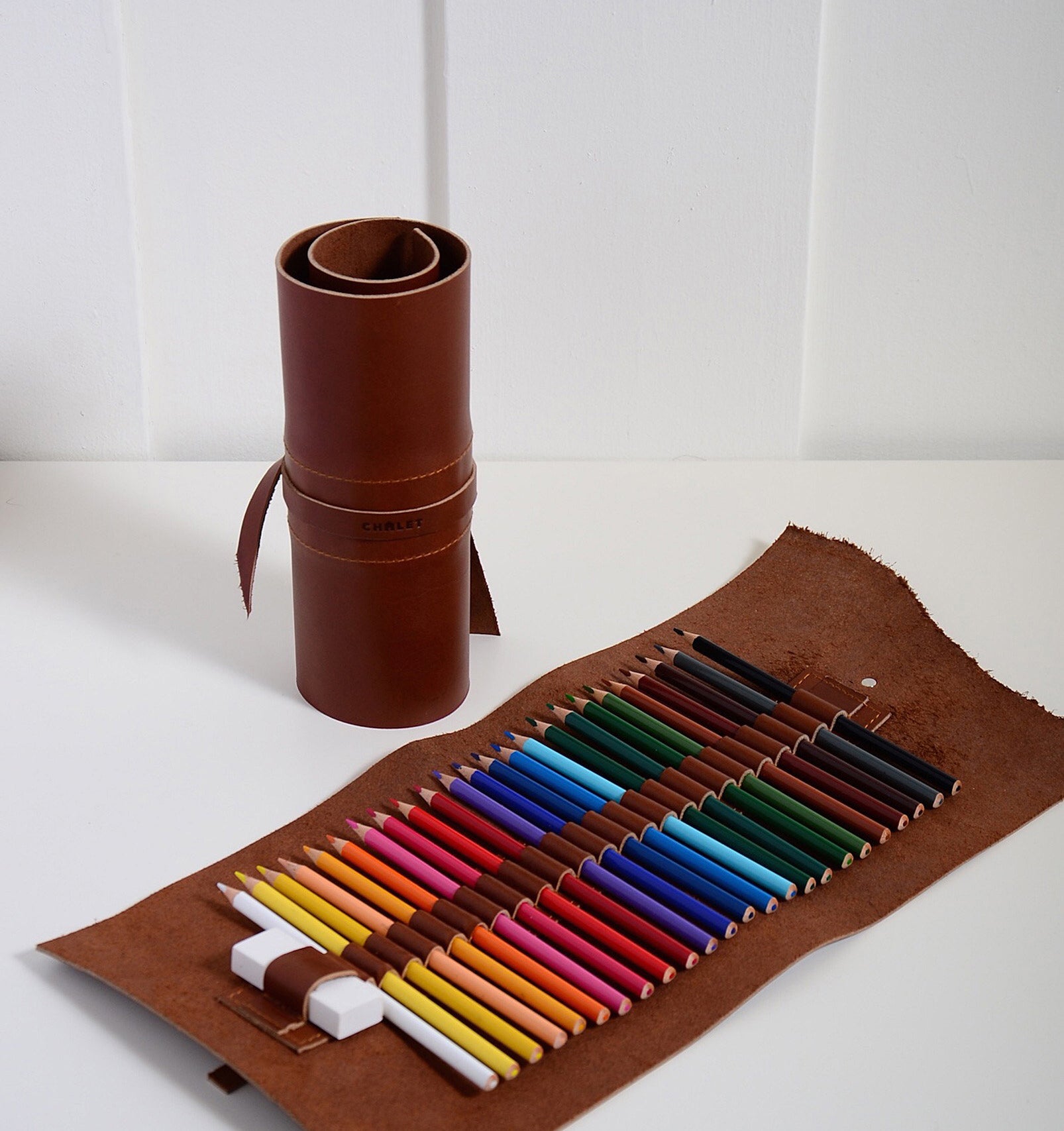 A leather roll plus one unravelled that show the coloured pencils inside