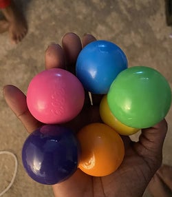 Reviewer holding the balls in pink, purple, orange, yellow, green, and blue colors