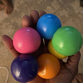 Reviewer holding the balls in pink, purple, orange, yellow, green, and blue colors