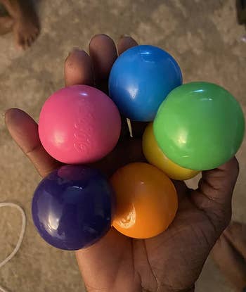 Reviewer holding the balls in pink, purple, orange, yellow, green, and blue colors