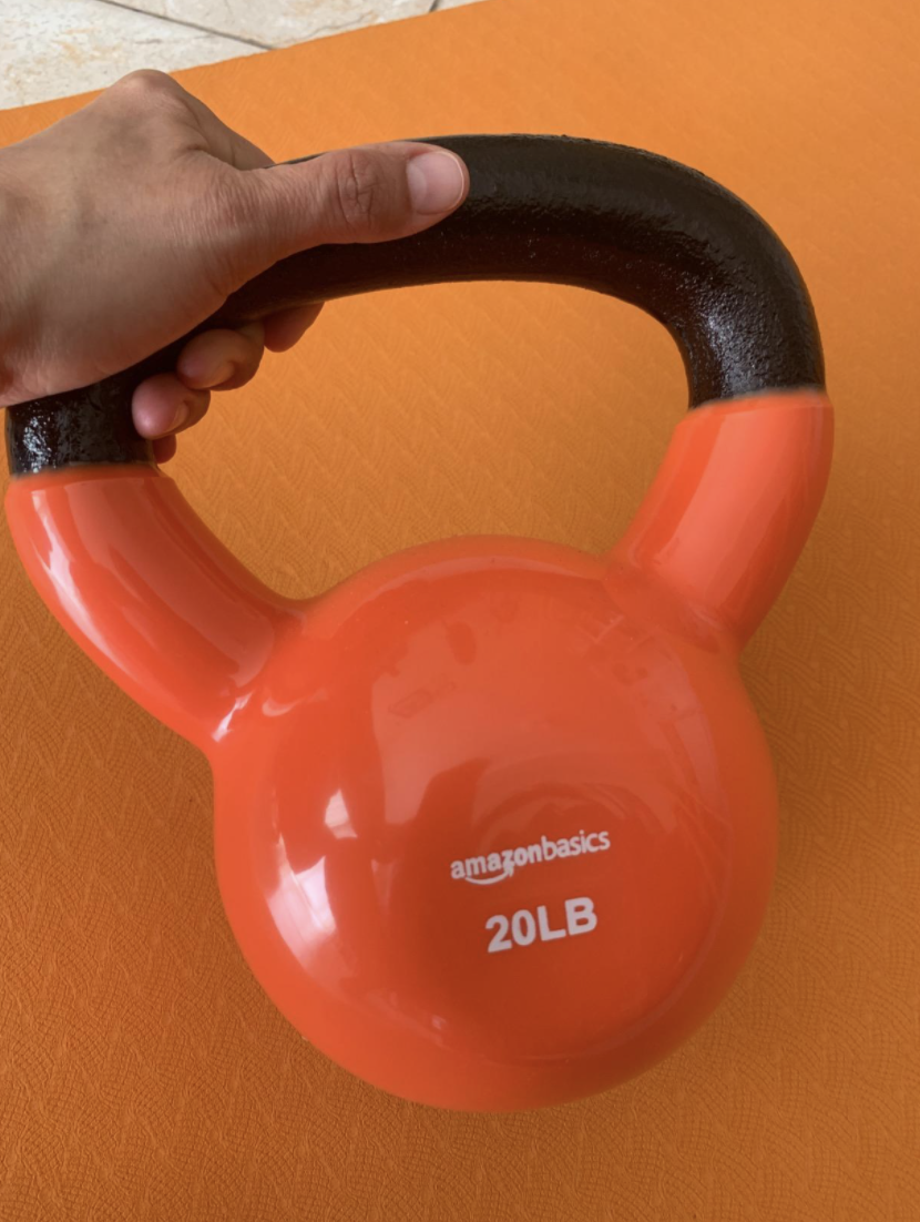 Reviewer holding an orange vinyl covered kettle bell weight