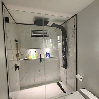 marble shower with the panel on one wall