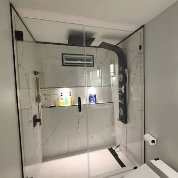 marble shower with the panel on one wall