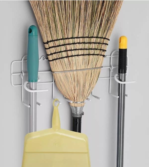 a white wire organizer hung on a wall holding cleaning supplies