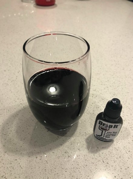 A reviewer&#x27;s photo of a glass of wine next to the drops