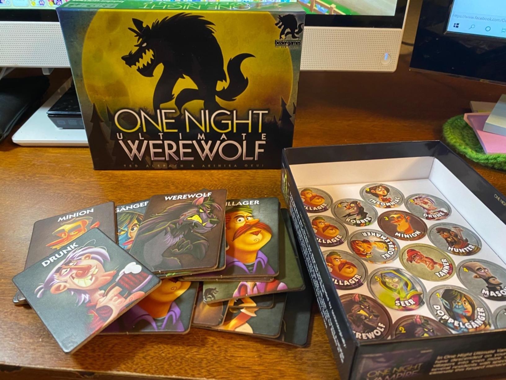 the &quot;one night ultimate werewolf&quot; card game on a table with the box open and cards laid out and tokens still in the box
