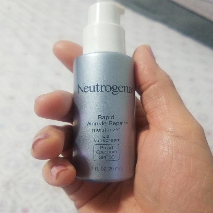 Reviewer holding a bottle of the moisturizer