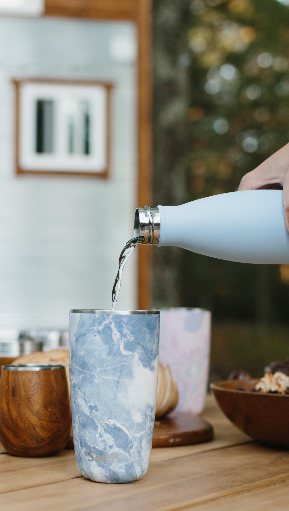 the blue granite tumbler on a countertop with a person pouring liquid into it from another water bottle