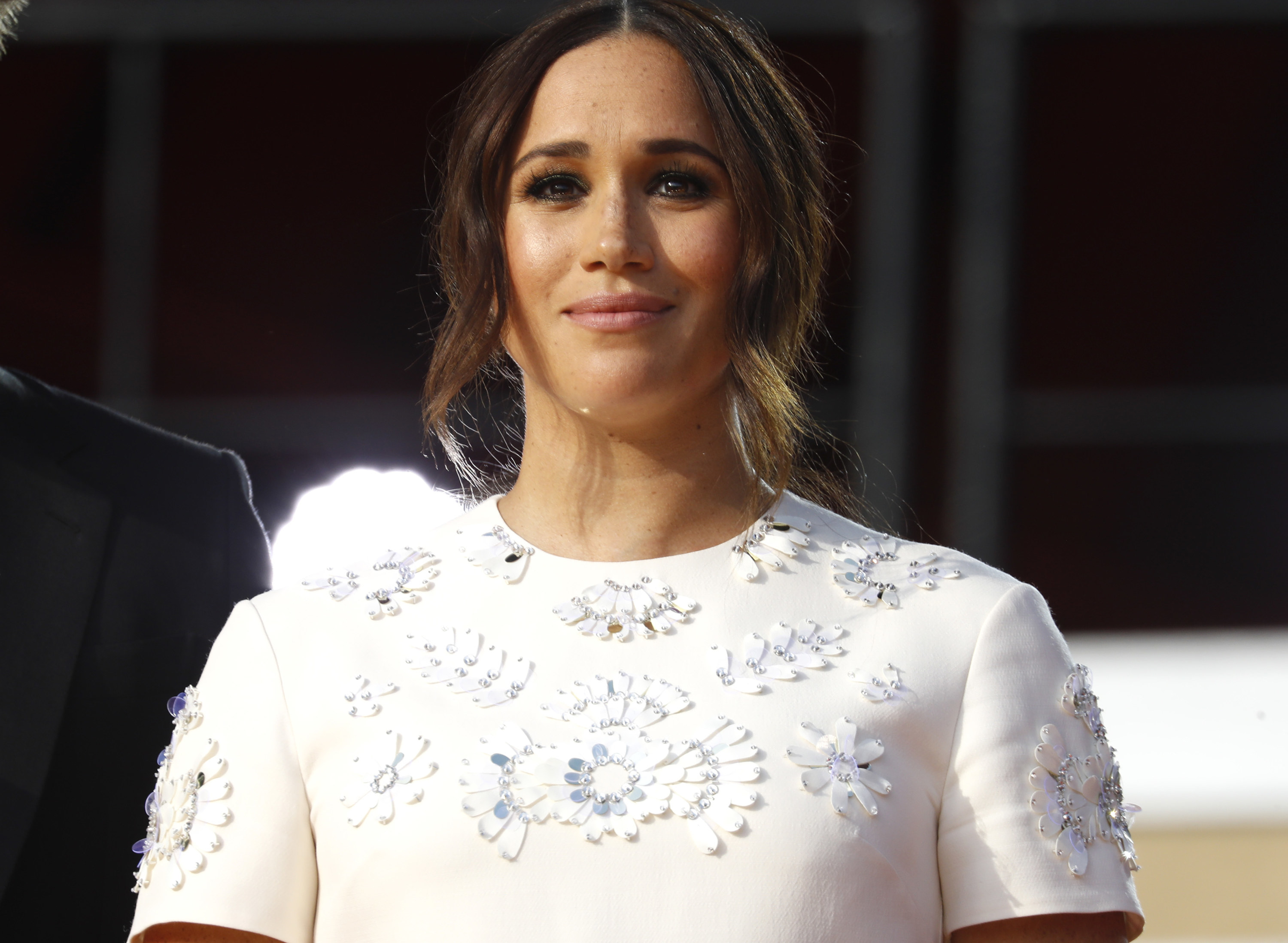 Meghan wears a white top with a circular pattern