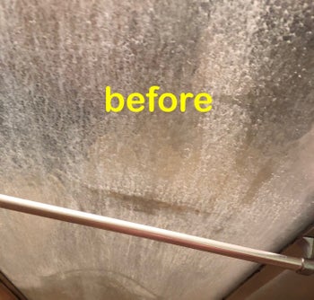 A reviewer's with cloudy shower door stained with hard water, before using the shower cleaner