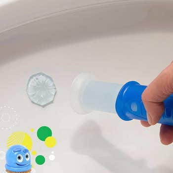 A hand stamping the circle of gel in the toilet