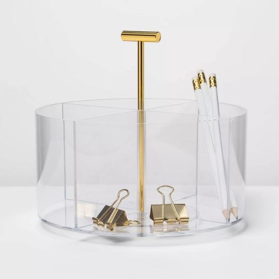 a round acrylic organizer with four sections and a gold bar in the middle