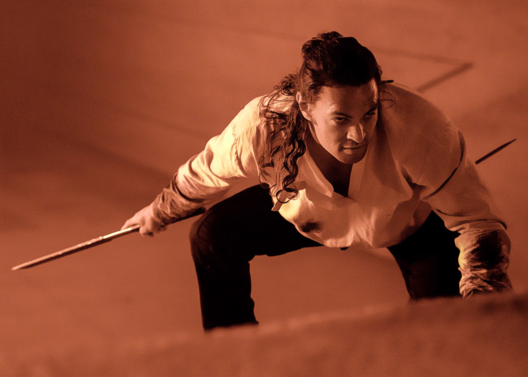 Jason Momoa holding a sword in the sand