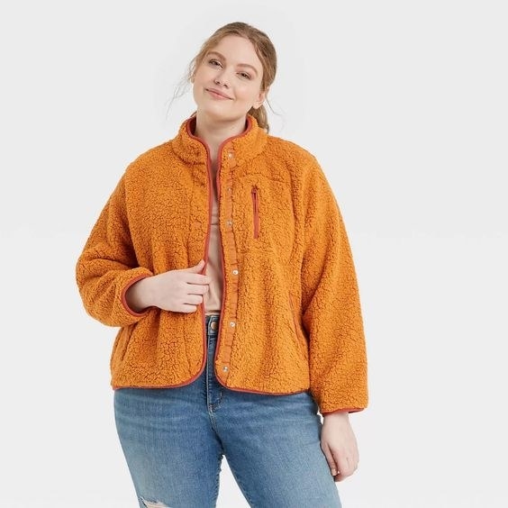 model in an orange fleece jacket with snap closure