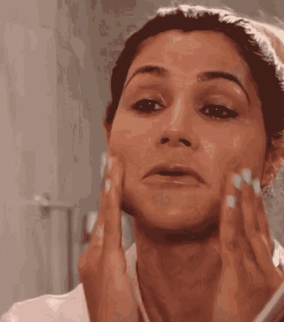 A woman applying lotion to her face