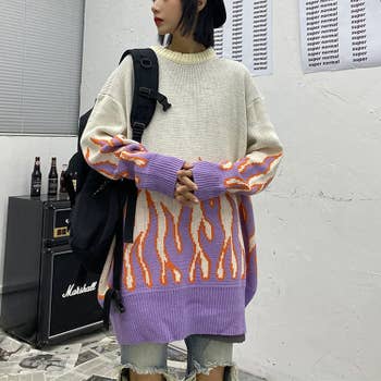 A model wearing the oversized sweater with purple flames on bottom and sleeves