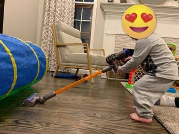 reviewer's kid using play dyson to vacuum