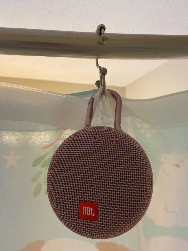 a reviewer's purple clip-on speaker attached to a shower curtain