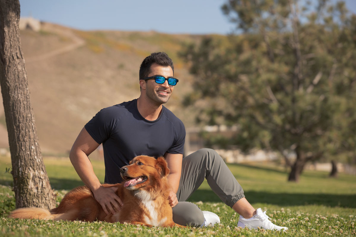 Smiling man wears Echo Frames glasses while at the park with his dog