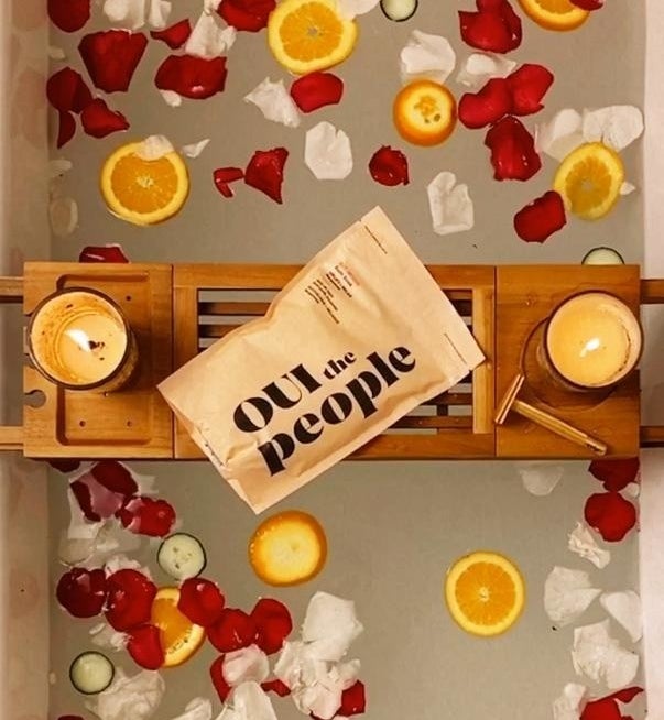 a pouch of oui the people bath soak on a tray over a bath tub