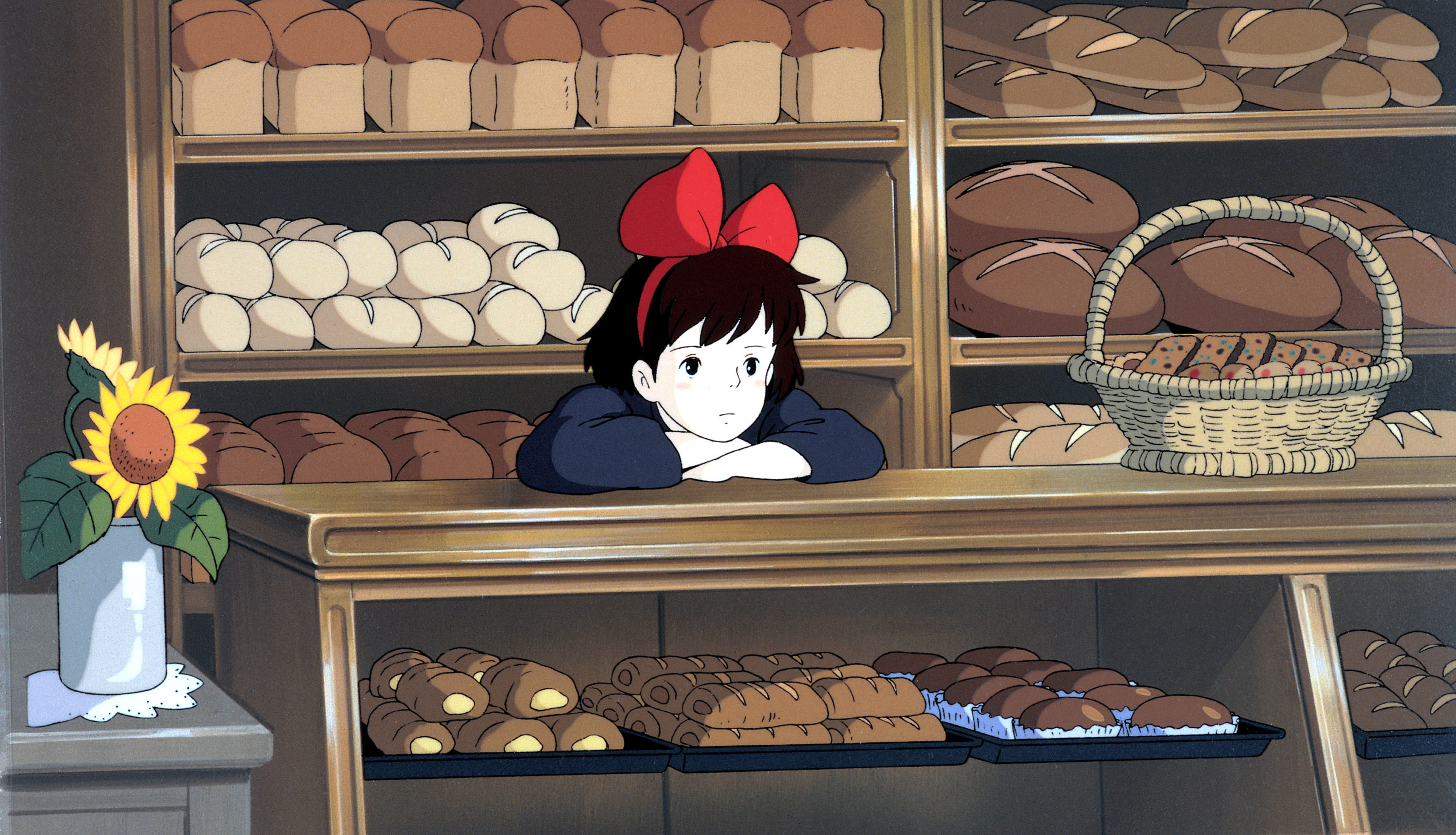 Kiki leaning on the counter of a bakery waiting for something