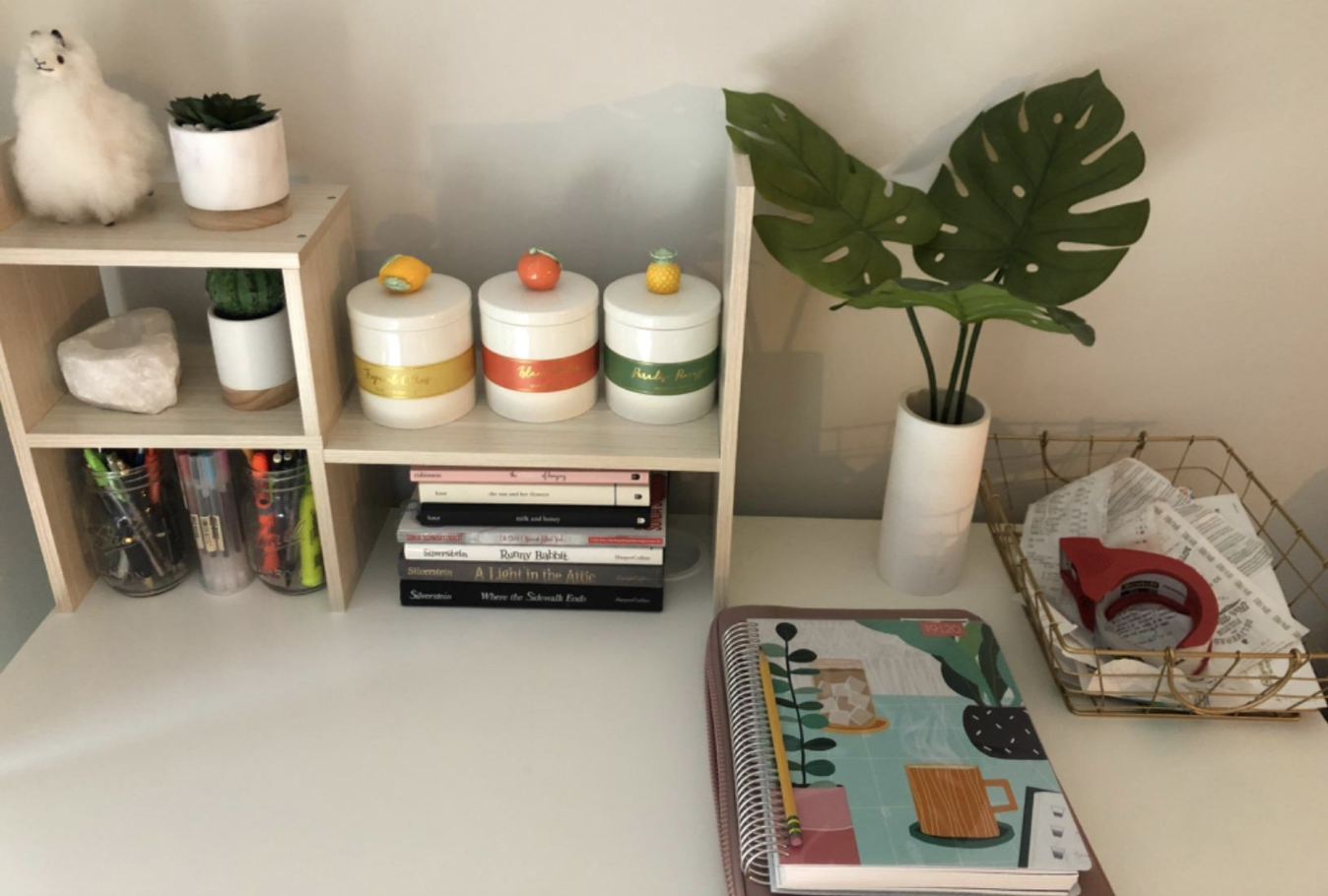 the light wood desk organizer holding various knickknacks on a desk with notebooks