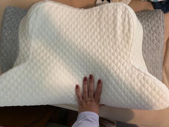 a different reviewer pressing their hand down on the pillow
