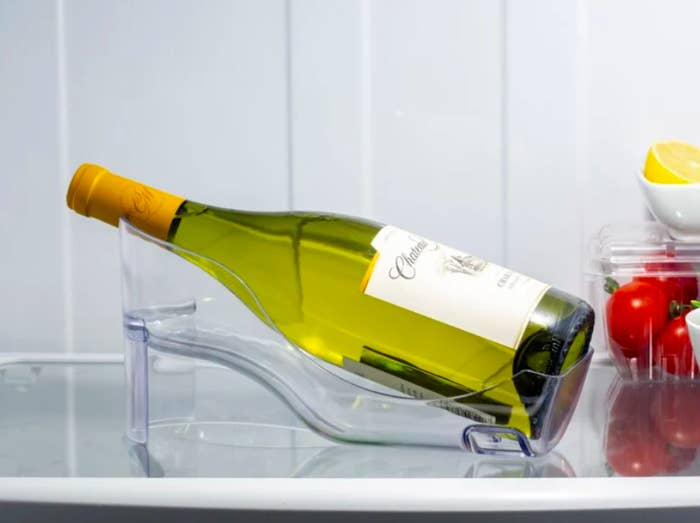 A clear wine bottle holder that allows the bottle to lay almost flat but at a slight angle, as it would in most wine cellars