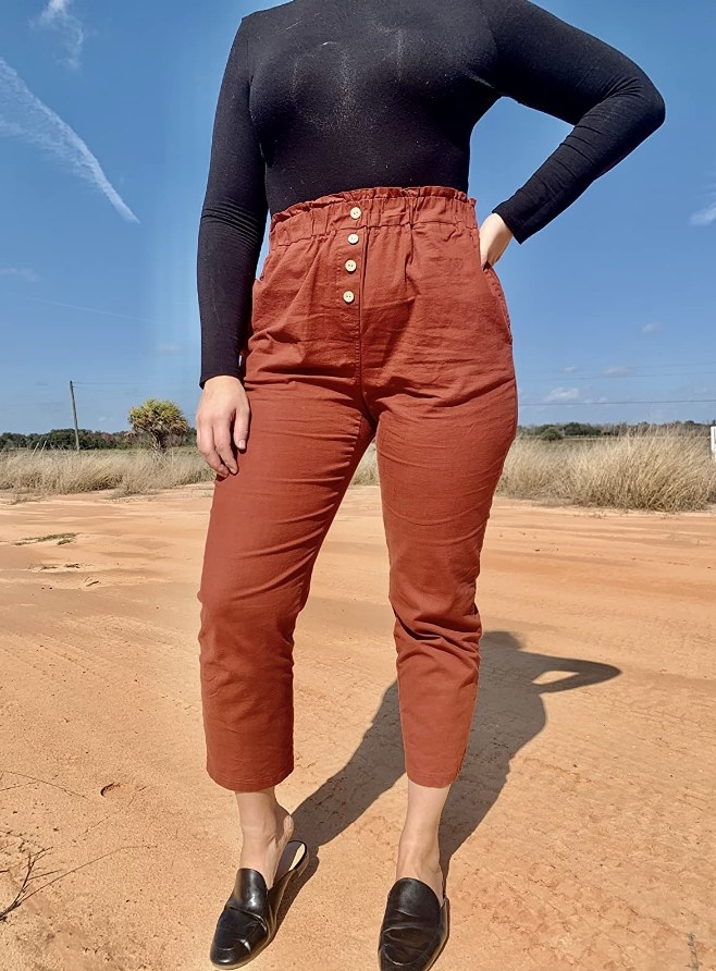 A reviewer wearing a pair of rust red high waisted cropped pants