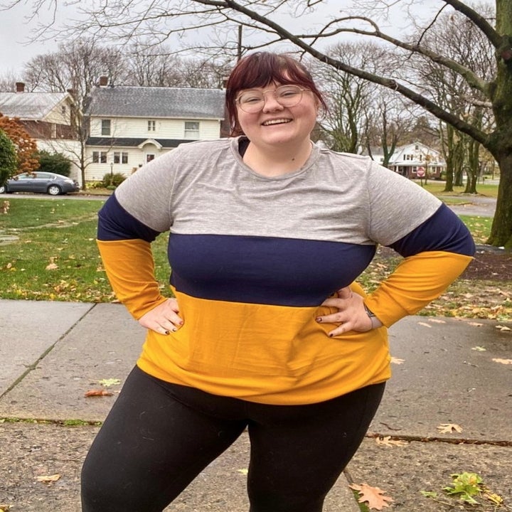 A reviewer wearing a grey/blue/yellow long sleeve crewneck