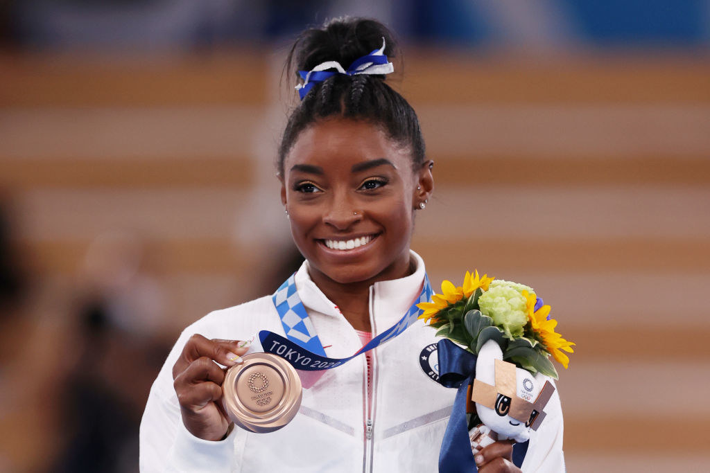 Smiling Simone holding up a medal and flowers