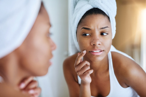 A woman examines her face.