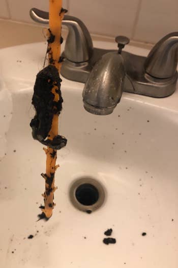 tool covered in clumps of reviewer's hair from drain
