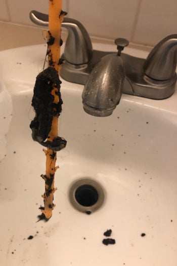 tool covered in clumps of hair from drain