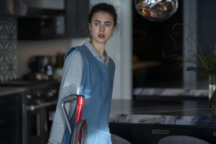 Margaret Qualley dressed in a maid&#x27;s uniform holding a Dyson vacuum in one of her clients&#x27; homes