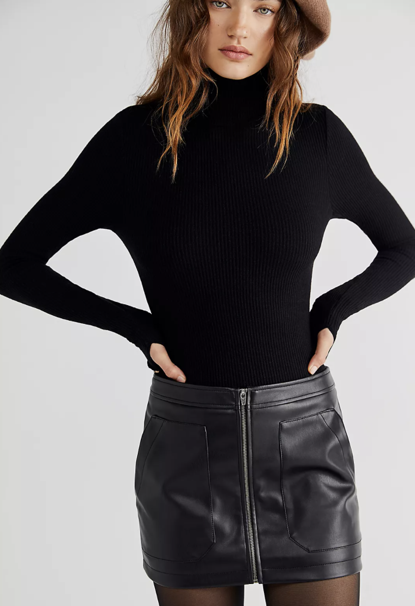 Model is wearing a black leather mini skirt with a black top