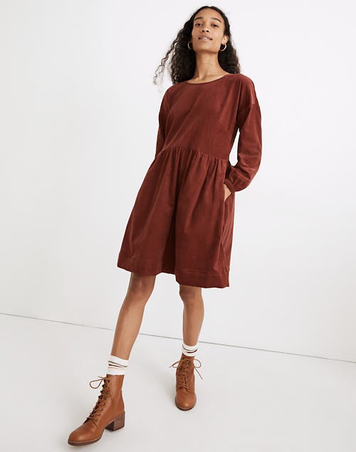 Model is wearing a rust colored corduroy mini dress with long sleeves and tan combat boots