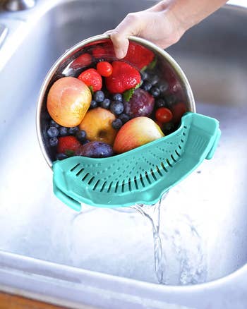 Bowl of fruit being strained through aqua clip-on colander