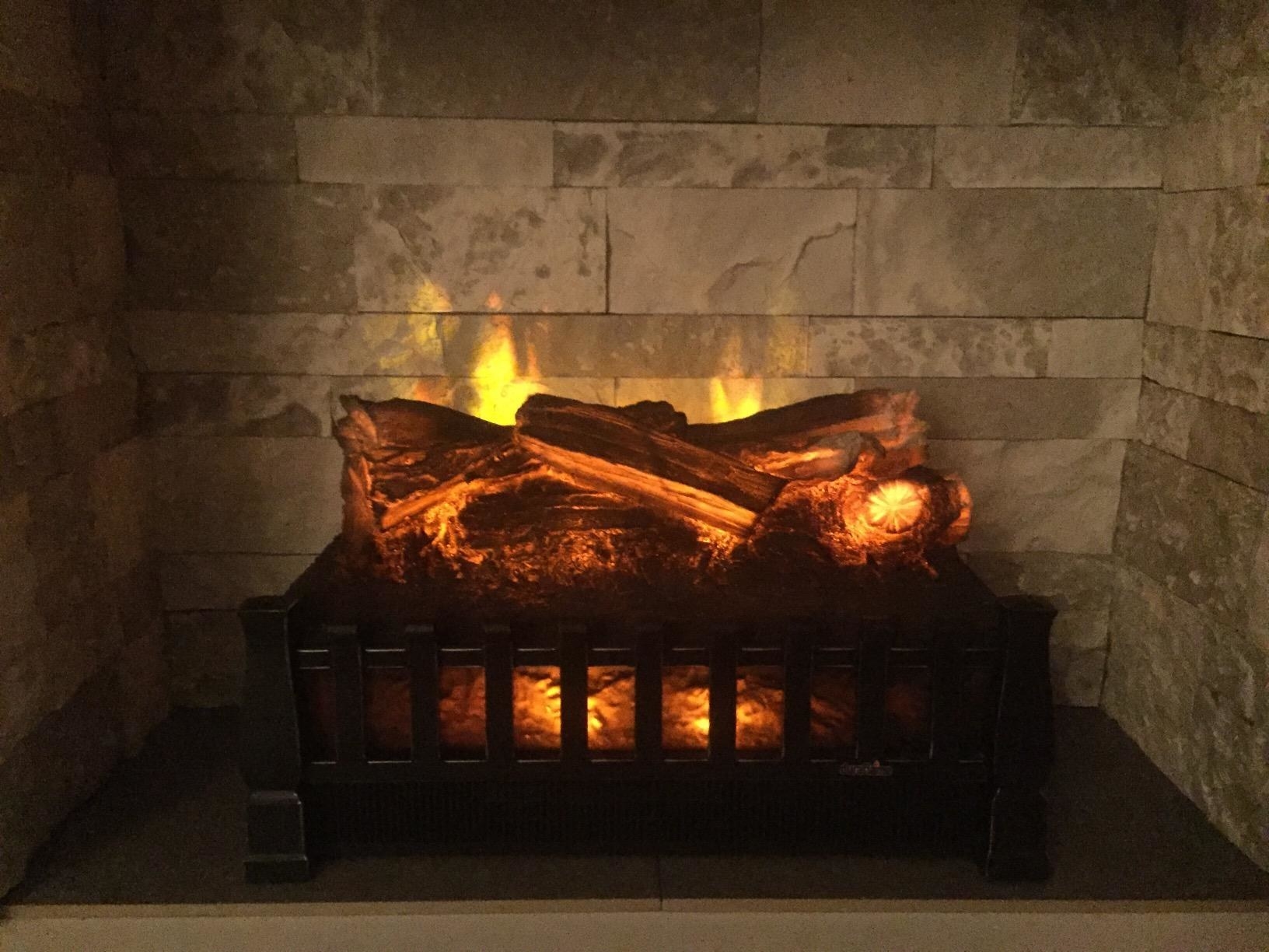 A reviewer&#x27;s electric fireplace placed inside their real one